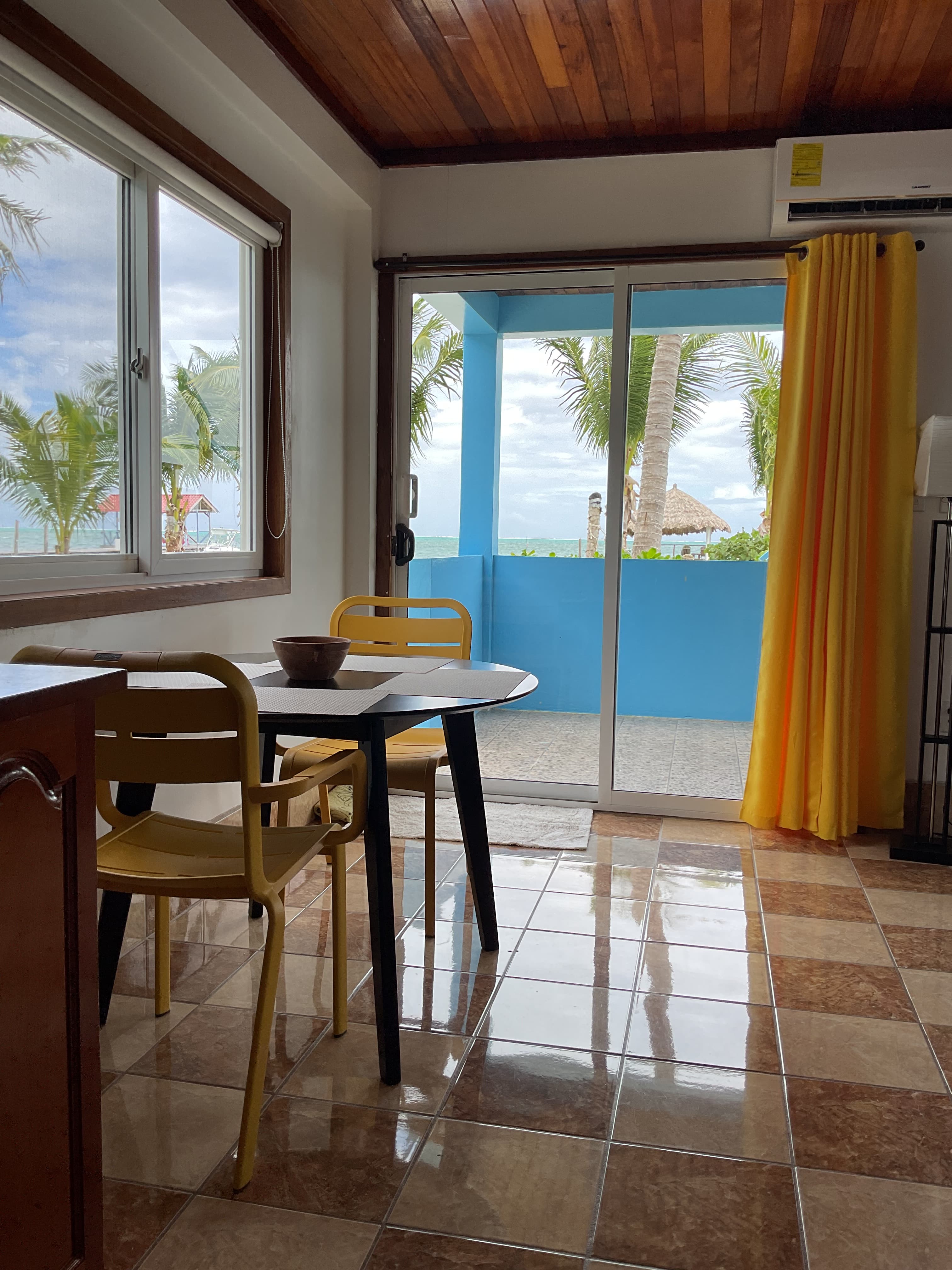 View of porch, ocean and beach from living area through sliding glass doors