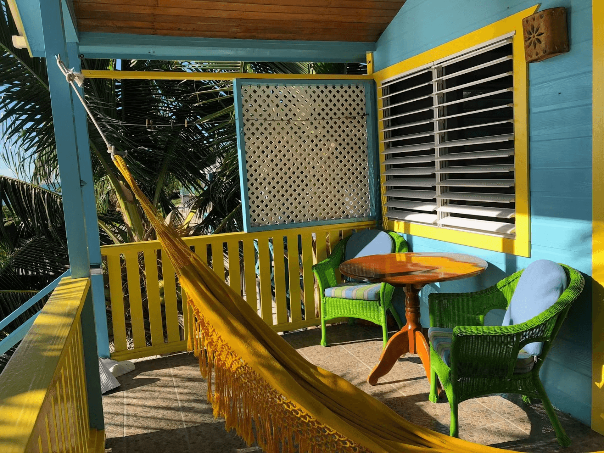 Brightly painted blue and yellow balcony with hammock and wicker chairs with cushions