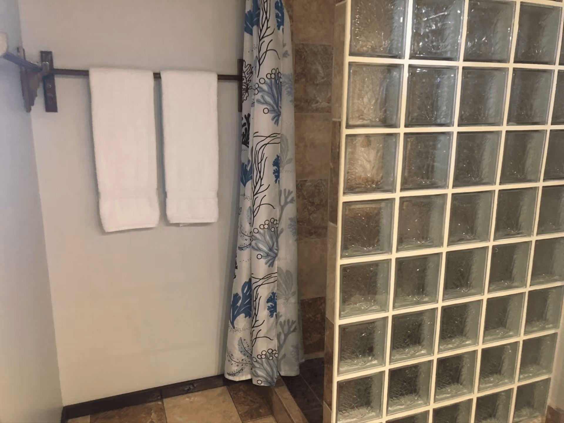 Enclosed shower with plush white bath towels hanging nearby