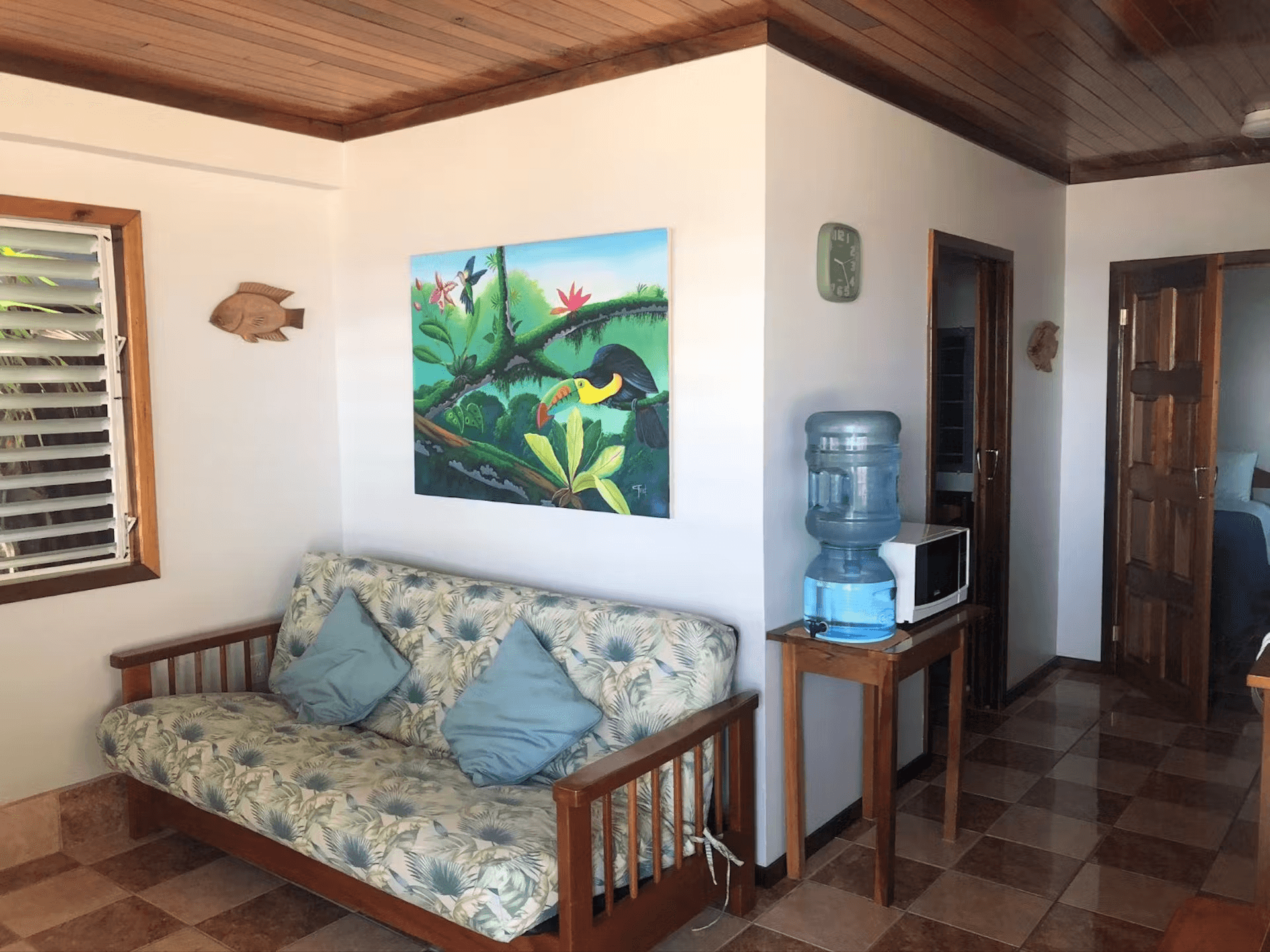 Sitting area with double futon, tropical artwork, and table with water cooler