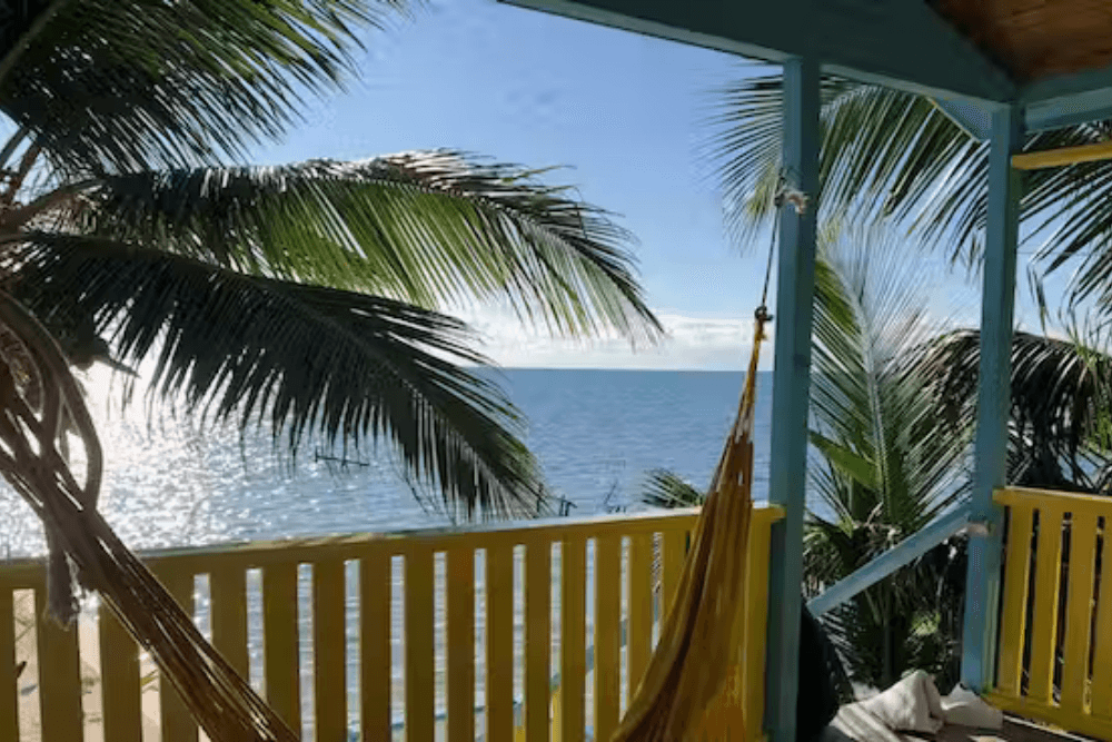 hammock stretched out on porch with palm trees overlooking ocean