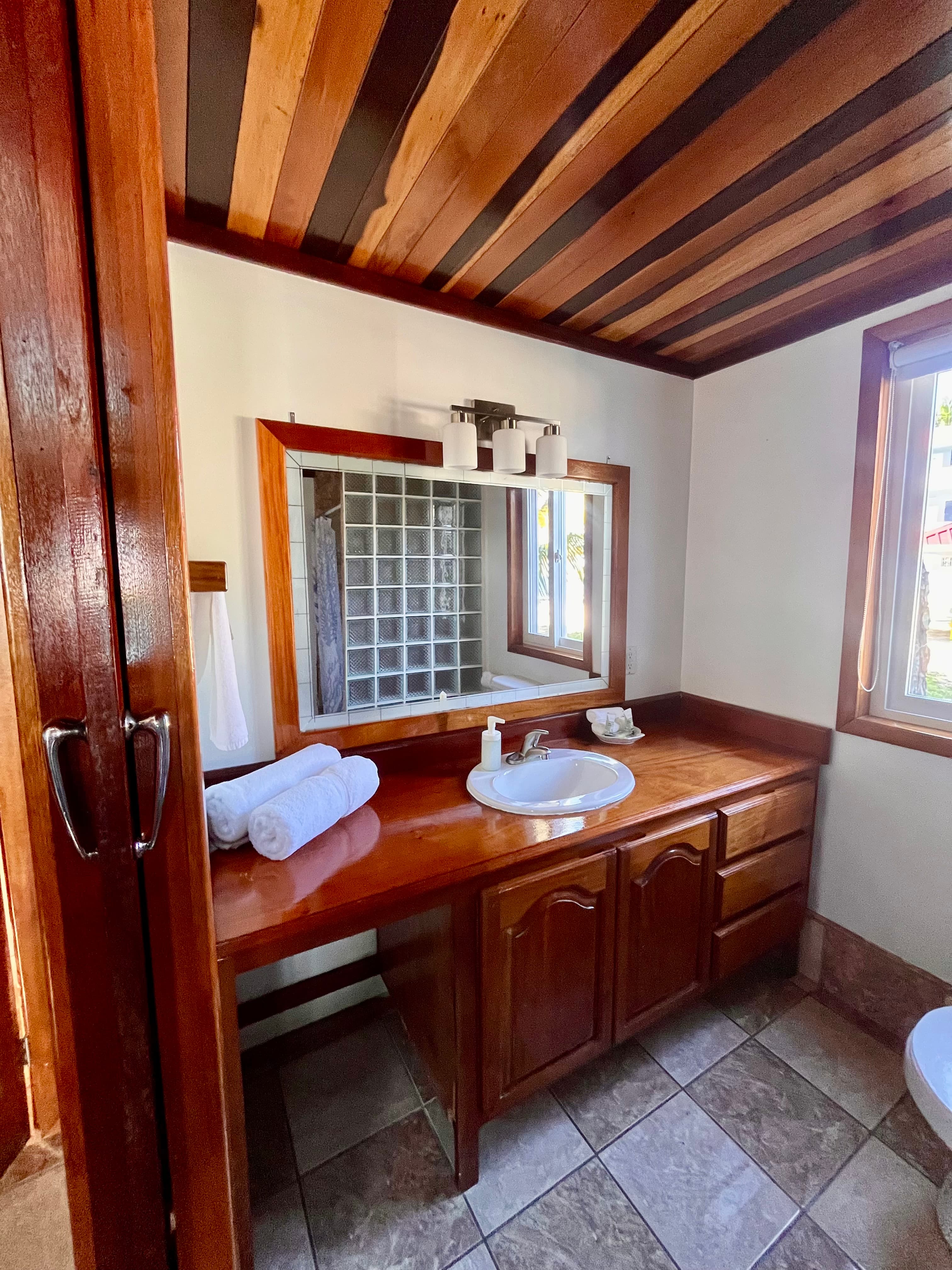 A warmly decorated bathroom featuring a wooden countertop, sink, and a large mirror.